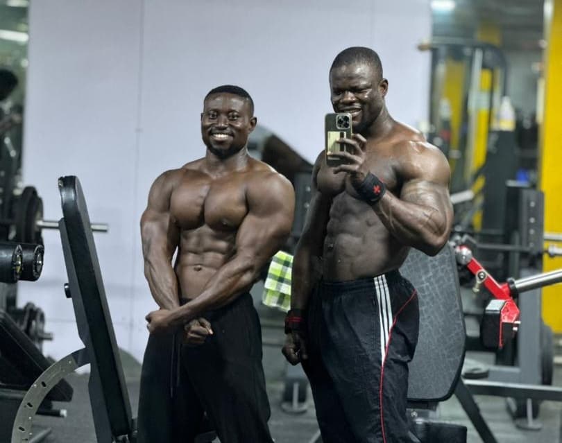 Two athletes posing together in the gym mirror